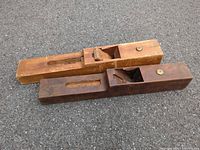 Two wooden jointer planes side by side on pavement