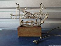 Full view of Schaefer Beer neon sign on rusted base with power cord visible