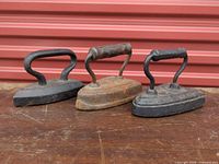 Front view of three sad irons showing size variation and handles