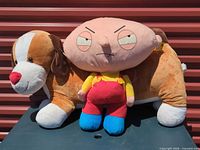 Stewie plush standing against elongated dog plush