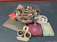 Lot overview with bowl of jewelry, compacts, bangles, bone rings card