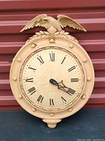 Front view of metal wall clock showing eagle crest and dial
