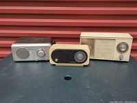 Three radios side by side: Emerson silver/brown, Realistic beige/black, GE beige clock radio