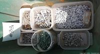 Five plastic tubs containing various nails and screws