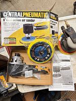 Boxed new sander, loose accessories and used sander visible