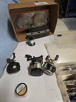 Three baitcasting reels, spare line spools, empty plastic box frame visible