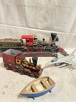 Group view showing steam locomotive on track, wooden train, jet model and rowboat
