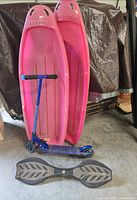 Group shot of two pink Torpedo sleds, blue kick scooter and black caster board