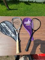 Two squash racquets out of covers on table