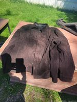 Front view of dark suede leather jacket laid flat