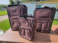 Front view of all three brown Eddie Bauer wheeled suitcases on table