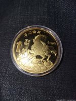 Obverse of gold-tone Year of the Horse token in plastic capsule
