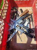 Knives, sharpener and peeler gathered in red crate