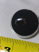 Top view of oval smoky topaz in display case beside ruler showing size