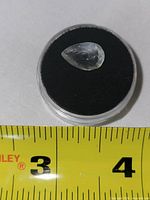 Pear-shape white topaz in case beside tape for scale