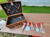 Picnic basket open with chisels arranged alongside showing interior lining and tool details