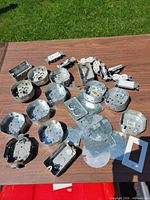 Group of metal junction boxes, blank covers, outlets and switches spread on table