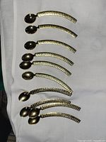 10 gold tone demitasse spoons laid out on cloth