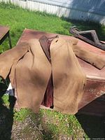 Full view of tan suede 3⁄4 length jacket laid flat