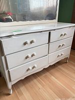 front view of white six-drawer dresser showing knobs, drawer fronts, and base