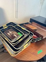 Stack of black floral trays, wooden tray and spoon on table