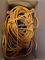 Box containing several orange extension cords