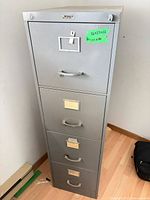 Front view of gray 4-drawer metal file cabinet with label holders and top lock