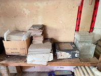 Bench with multiple stacks and boxes of assorted tiles