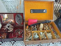 two jewelry boxes open with assorted costume jewelry inside
