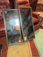 Two framed marbled mirrors leaning against chair