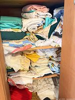 Cupboard shelves filled with folded assorted sheets and textiles