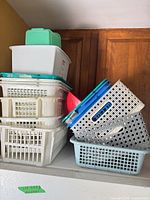 Stack of assorted plastic baskets and bins on appliance