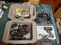 All four power tools laid out with their cases and accessories visible on table