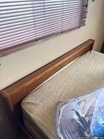 Headboard, mattress and blinds visible