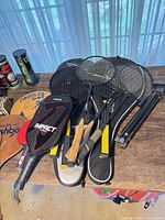 Group of rackets and paddles including badminton, tennis and paddleball items