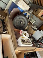 Overview of workbench showing two tires, thermostat package, cup of brass knobs