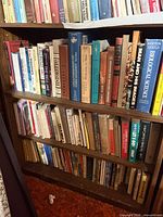 Three shelves densely packed with hardcover and paperback books