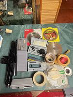 Overhead view of entire lot showing jack, time switch, hole saw kit, stapler, saw blades, tape rolls