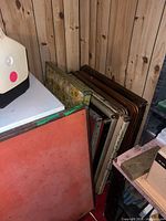 Stack of assorted vintage folding tables leaning against wall