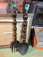 Full view of carved wooden fork and spoon leaning against wall art