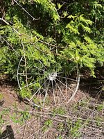 Full view of the painted metal wagon wheel leaning in foliage