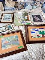 Group shot of all seven framed artworks on bed