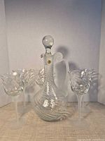 Decanter with stopper centered among five stemmed glasses