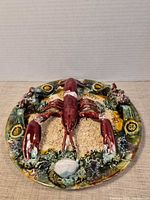 Front view of glazed ceramic plate showing full lobster and surrounding sea-life relief