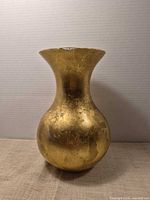 Front view of gold ceramic vase showing distressed finish