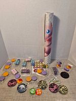 Entire assortment laid out with rolled playmat in tube upright, showing tokens, dice, discs and chits