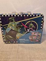 Front view of metal lunchbox tin with cardboard sleeve, Iron Treads and Iron Valiant artwork visible
