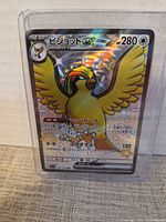 Front view of Japanese Pidgeot ex holographic card in protective sleeve
