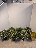 Front view of four faux plants and stacked gold planters