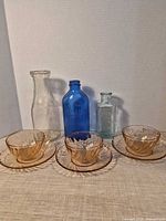 Full lot: three teacups with saucers in front of three bottles